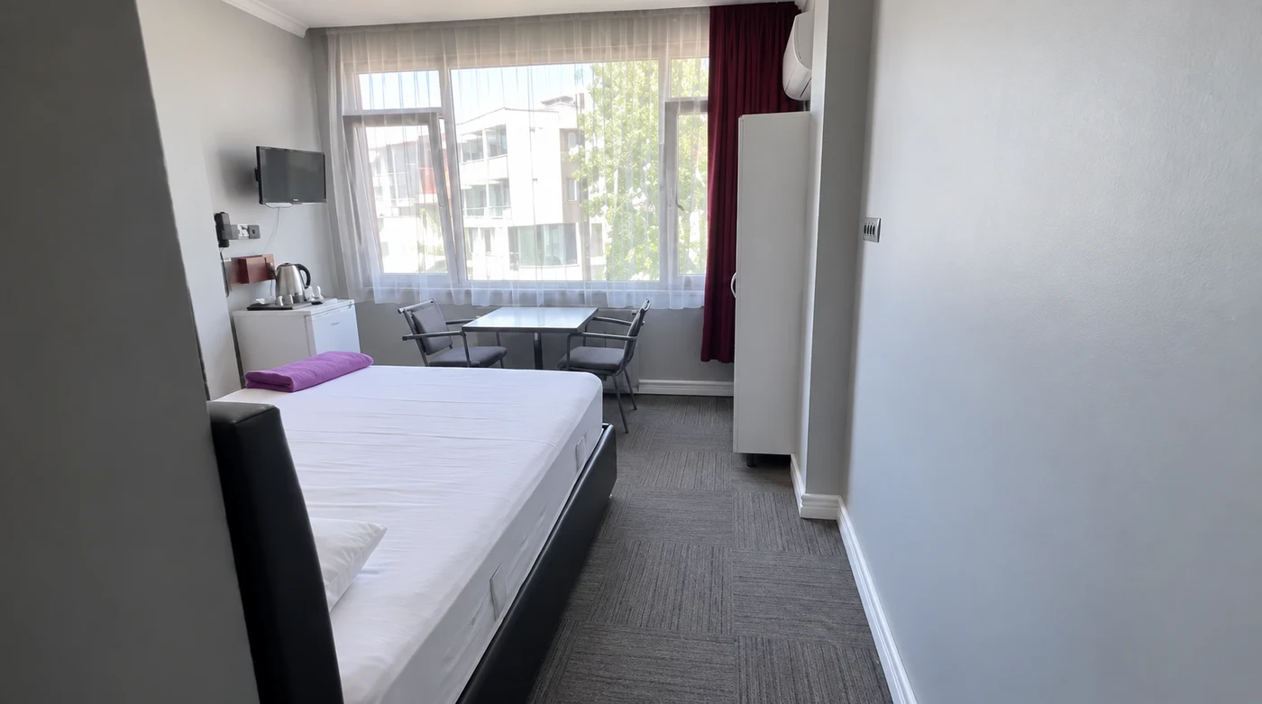İkon Otel odasında yatak, pencere önü ve oturma alanı